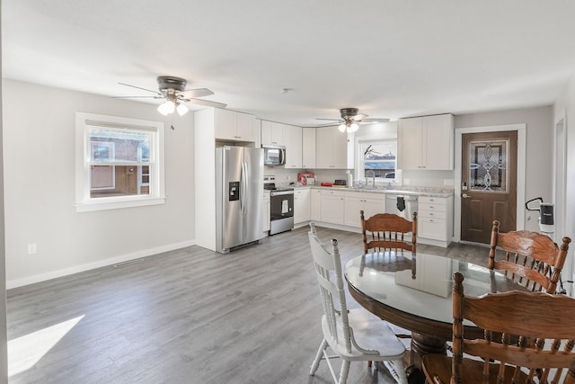 dining area with light wood finished floors, visible vents, baseboards, and a ceiling fan