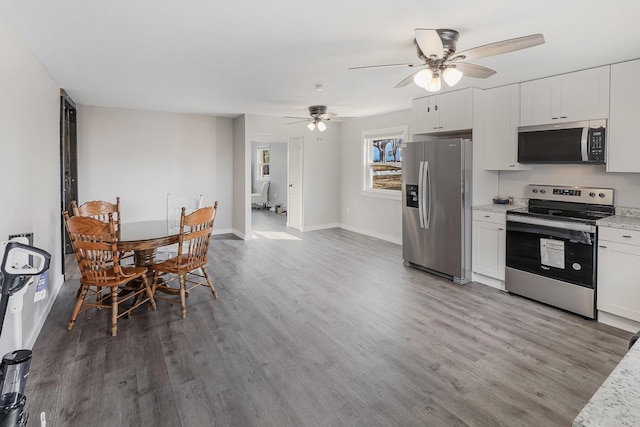 kitchen featuring stainless steel appliances, white cabinetry, baseboards, light wood-style floors, and light stone countertops