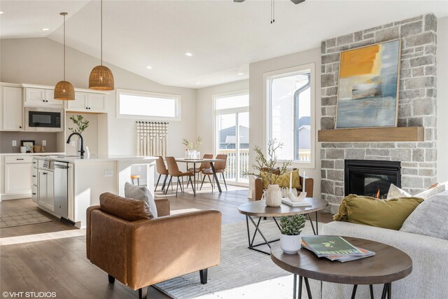 living room featuring lofted ceiling, sink, hardwood / wood-style flooring, ceiling fan, and a fireplace