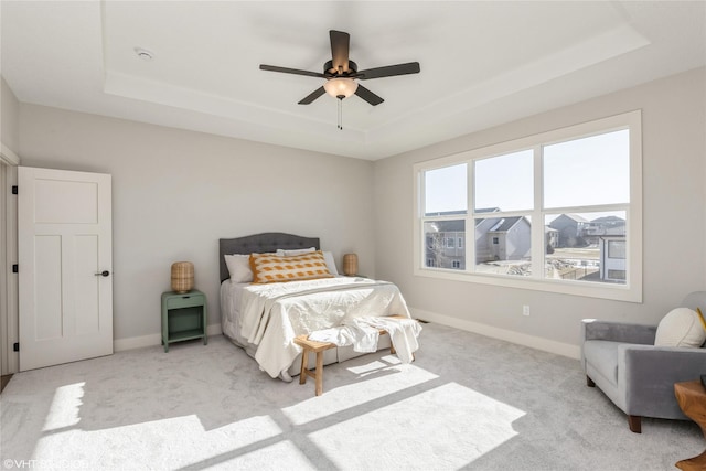 carpeted bedroom featuring a raised ceiling and ceiling fan