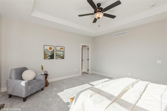 carpeted bedroom with a tray ceiling and ceiling fan