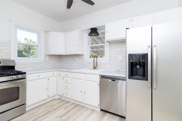 kitchen with decorative backsplash, white cabinetry, appliances with stainless steel finishes, and light hardwood / wood-style flooring