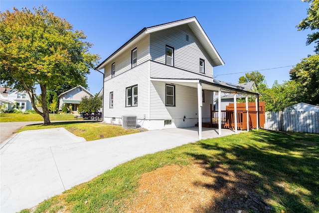 back of property with a lawn and central AC