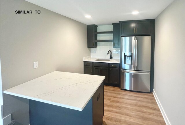 kitchen with decorative backsplash, sink, stainless steel fridge, and light hardwood / wood-style flooring