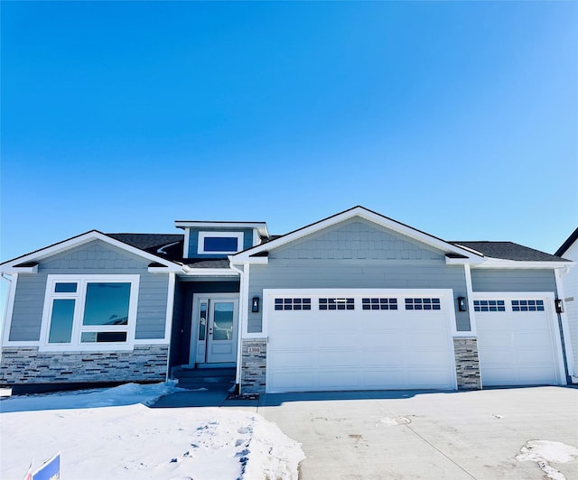 view of front of home featuring entry steps, stone siding, an attached garage, and driveway