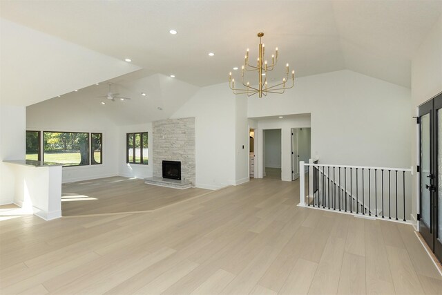 10318 NW 106th Ave, Granger, IA 50109 - unfurnished living room featuring ceiling fan with notable chandelier, light hardwood / wood-style flooring, a stone fireplace, and high vaulted ceiling