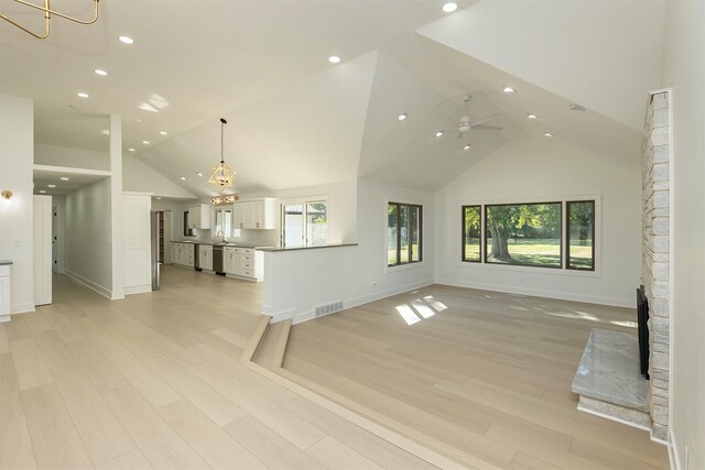 10318 NW 106th Ave, Granger, IA 50109 - unfurnished living room featuring ceiling fan with notable chandelier, light hardwood / wood-style floors, and high vaulted ceiling