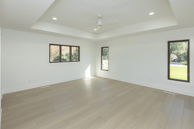 spare room with ceiling fan, a healthy amount of sunlight, and a tray ceiling