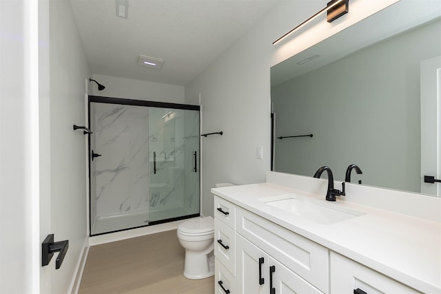 bathroom with hardwood / wood-style floors, vanity, toilet, and a shower with shower door