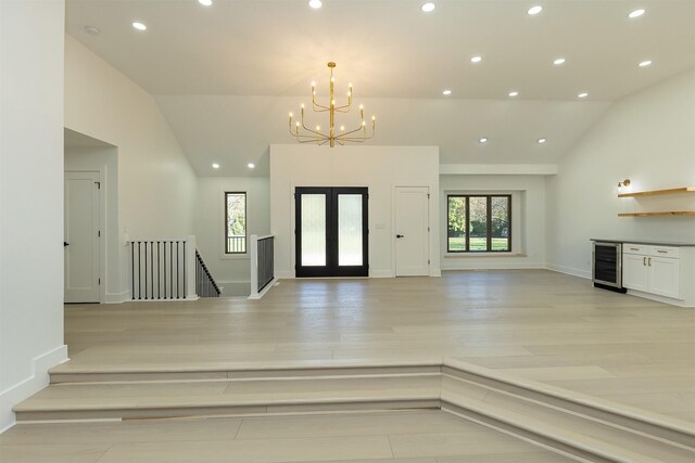 entryway with vaulted ceiling, wine cooler, plenty of natural light, and a notable chandelier