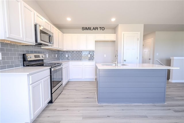 kitchen featuring a kitchen island with sink, sink, light wood-type flooring, white cabinetry, and stainless steel appliances