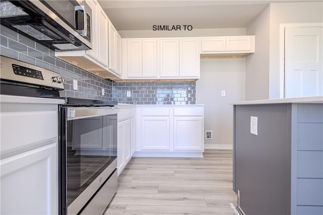 kitchen with white cabinets, appliances with stainless steel finishes, light wood-type flooring, and backsplash