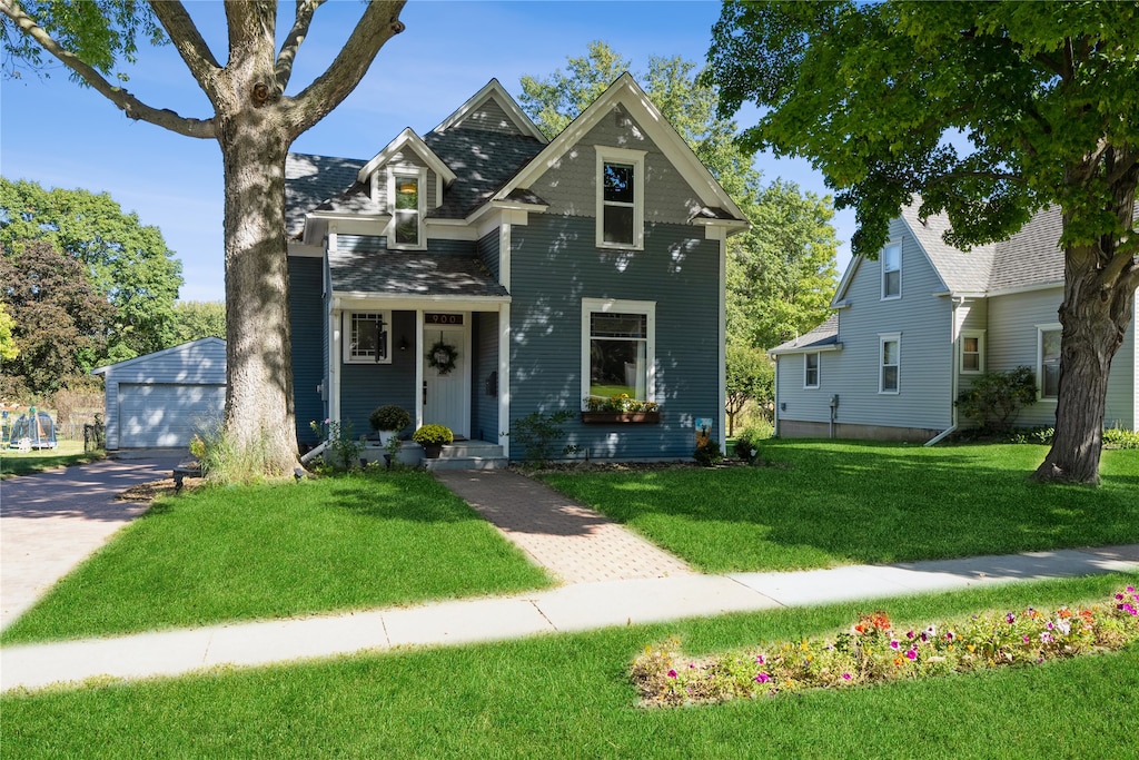 view of front of property featuring an outbuilding, a garage, and a front yard