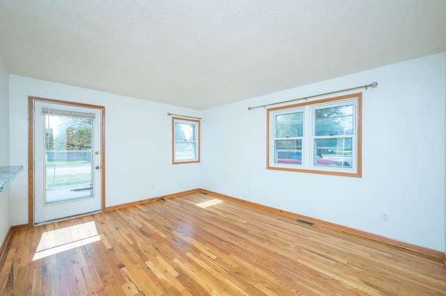 spare room with light wood-type flooring and a textured ceiling