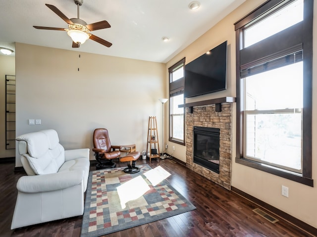 living room with a stone fireplace, ceiling fan, and dark hardwood / wood-style flooring