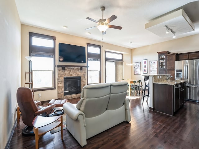 living room featuring a fireplace, dark hardwood / wood-style flooring, track lighting, and plenty of natural light