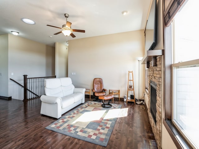 living room with a fireplace, dark hardwood / wood-style flooring, and ceiling fan