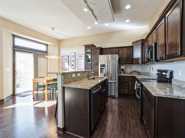 kitchen featuring hanging light fixtures, a kitchen island with sink, stainless steel appliances, and a breakfast bar