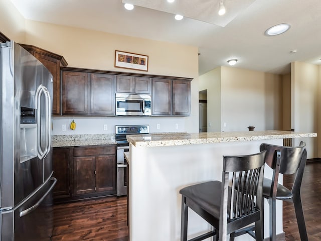 kitchen featuring a breakfast bar area, stainless steel appliances, and dark hardwood / wood-style flooring