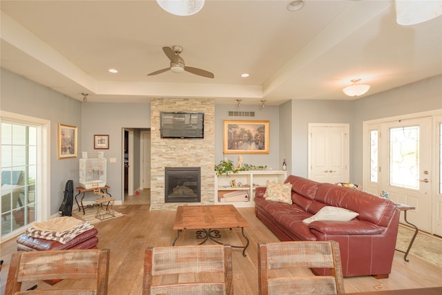 living room featuring light hardwood / wood-style floors, a fireplace, ceiling fan, and plenty of natural light