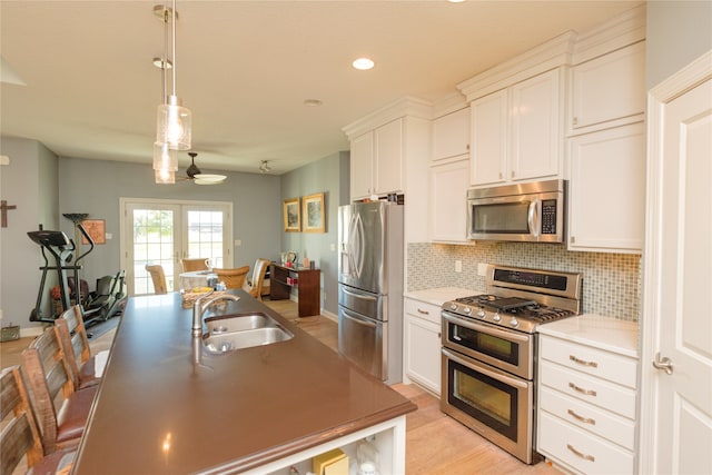 kitchen with white cabinets, pendant lighting, sink, appliances with stainless steel finishes, and decorative backsplash