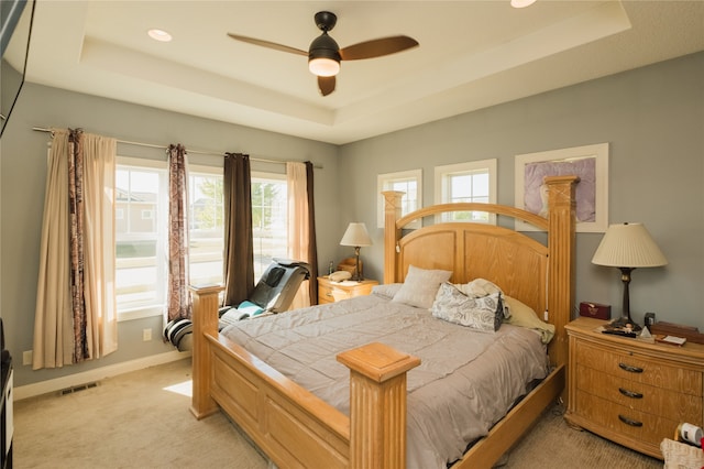 carpeted bedroom with ceiling fan and a tray ceiling