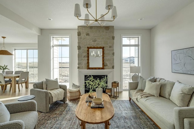 living area featuring hardwood / wood-style flooring, a stone fireplace, and an inviting chandelier