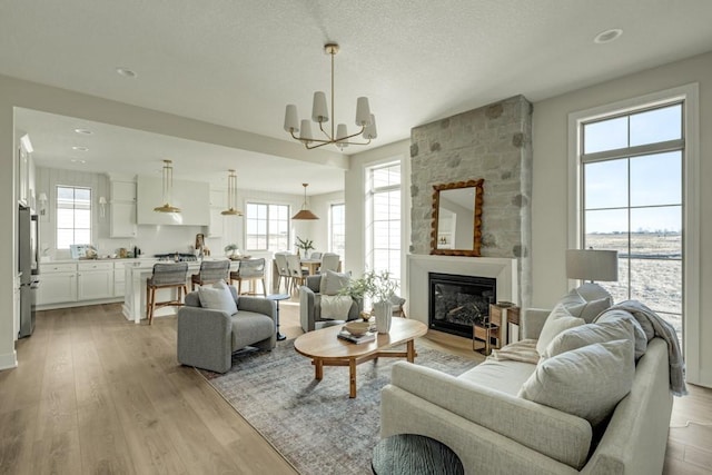 living room featuring light wood-type flooring, a notable chandelier, and a large fireplace