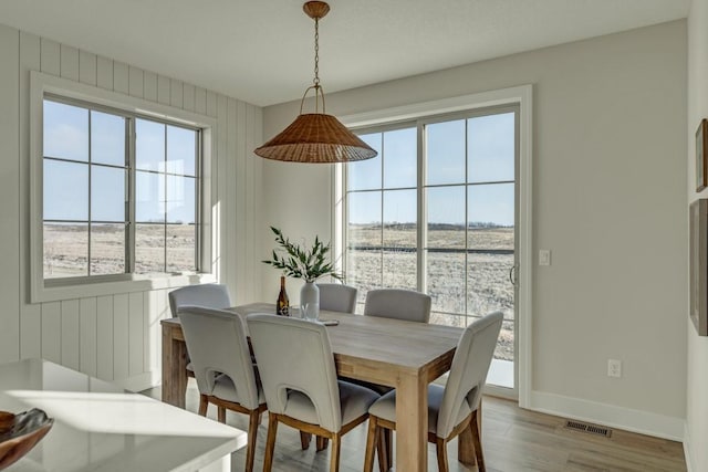 dining area featuring wood walls and light hardwood / wood-style flooring