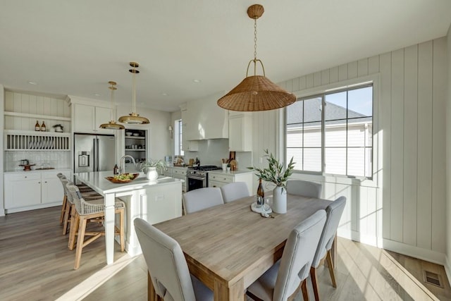 dining space with light hardwood / wood-style floors and wooden walls