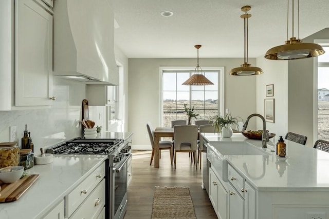 kitchen featuring light stone countertops, pendant lighting, white cabinets, extractor fan, and stainless steel stove