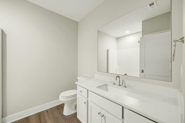 bathroom with toilet, hardwood / wood-style flooring, walk in shower, and vanity