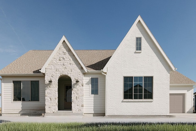 view of front of property with a garage, a shingled roof, and brick siding