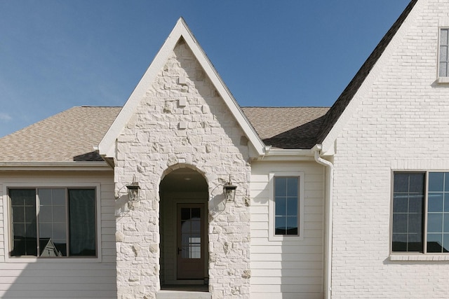 property entrance featuring roof with shingles