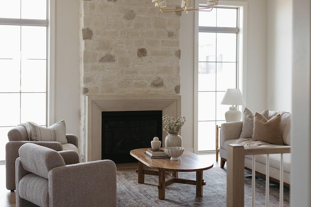 living area with a fireplace, wood finished floors, and an inviting chandelier