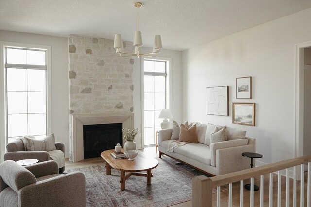 living room with a large fireplace, an inviting chandelier, and wood finished floors