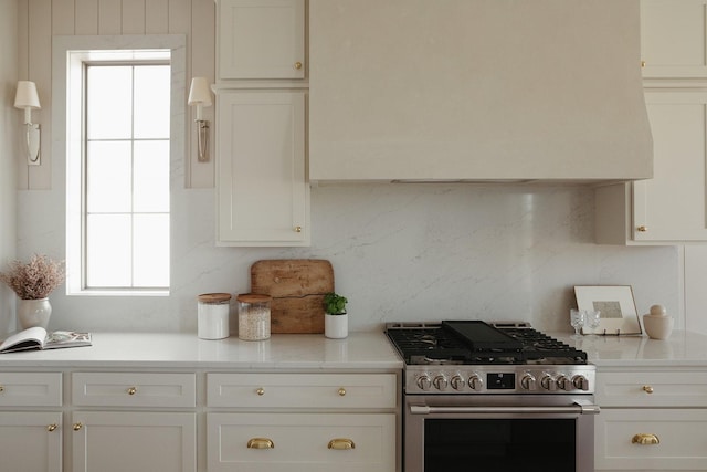 kitchen featuring tasteful backsplash, light countertops, stainless steel range with gas stovetop, and white cabinetry