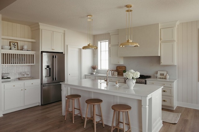 kitchen with open shelves, light countertops, appliances with stainless steel finishes, a sink, and wood finished floors