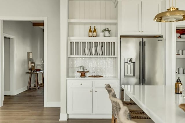 kitchen with light countertops, white cabinetry, wood finished floors, stainless steel fridge, and baseboards