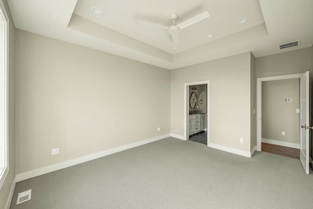 unfurnished bedroom featuring visible vents, baseboards, a raised ceiling, and carpet flooring