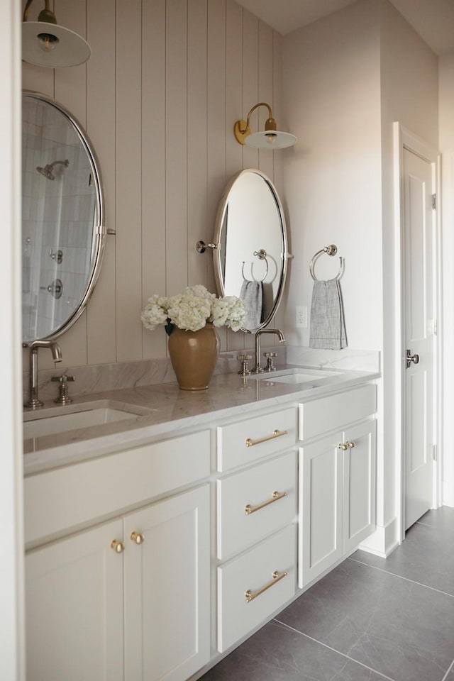 full bathroom featuring a sink, a tile shower, and double vanity