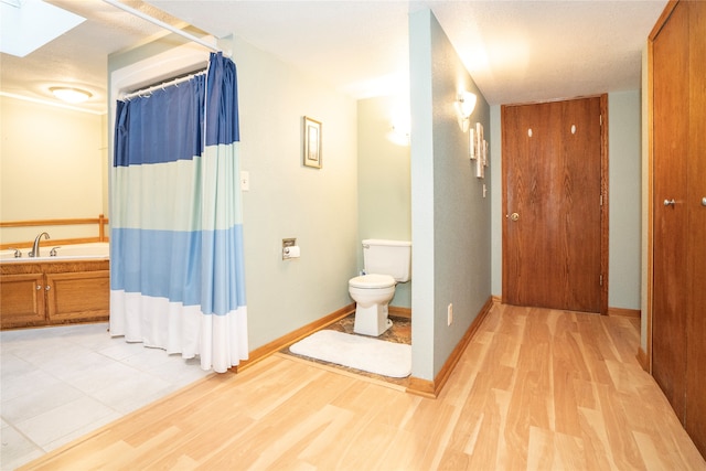 bathroom featuring a skylight, a bath, hardwood / wood-style flooring, and toilet