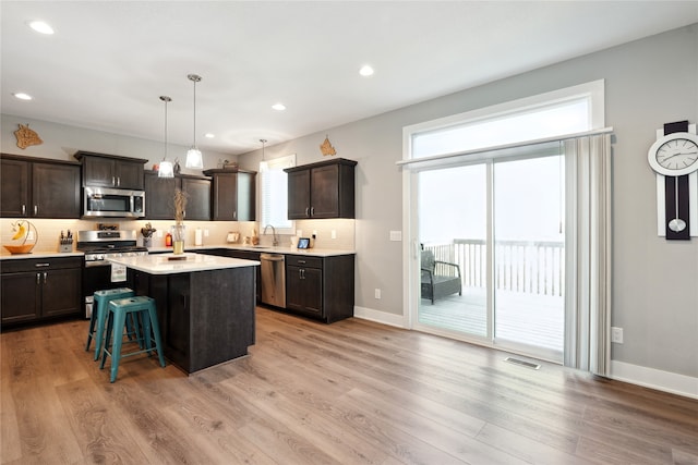 kitchen with dark brown cabinets, a center island, light hardwood / wood-style flooring, and stainless steel appliances