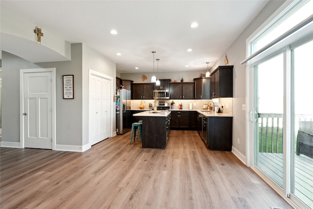 kitchen with sink, a kitchen island, decorative light fixtures, stainless steel appliances, and a kitchen bar