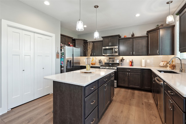 kitchen with light hardwood / wood-style flooring, stainless steel appliances, hanging light fixtures, and sink