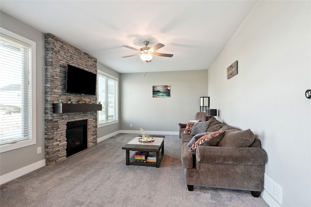 living room featuring carpet, a stone fireplace, and ceiling fan