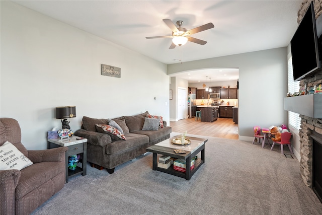 living room with ceiling fan, light hardwood / wood-style flooring, and a fireplace