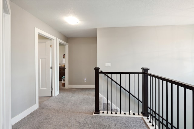 corridor featuring a textured ceiling and light colored carpet