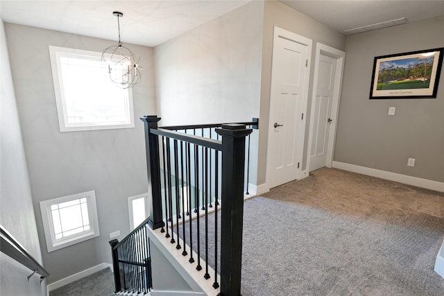 stairs with carpet floors and a notable chandelier