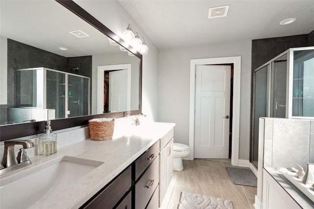 bathroom featuring wood-type flooring, a shower with shower door, vanity, and toilet